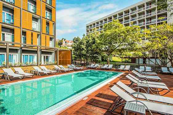 Uima-allas, jossa aurinkotuoleja ja taustalla rakennuksia. (Tekoälyn luoma teksti)