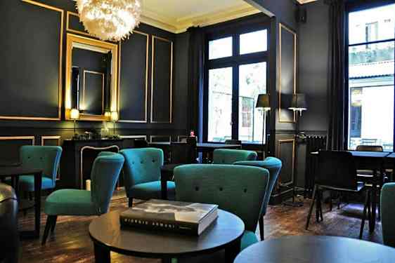 Tyylikkäästi sisustettu huone, jossa istuinryhmiä ja sinisiä nojatuoleja sekä suuret ikkunat. (Tekoälyn luoma teksti)