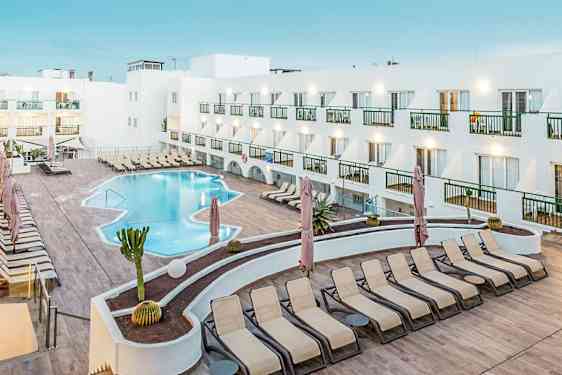 Hotellin uima-allas aurinkotuoleineen ja valkoisen rakennuksen ympäröimänä. (Tekoälyn luoma teksti)