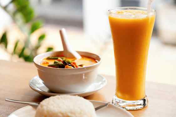 Kulho keltaista currya, lautanen riisiä ja lasi keltaista juomaa. (Tekoälyn luoma teksti)