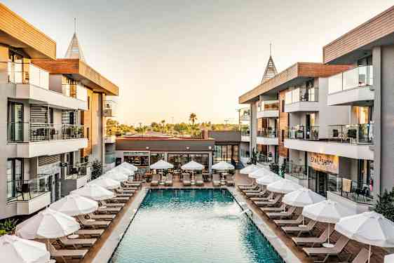 Hotellialue, jossa uima-allas ja aurinkotuoleja rakennusten ympäröimänä. (Tekoälyn luoma teksti)