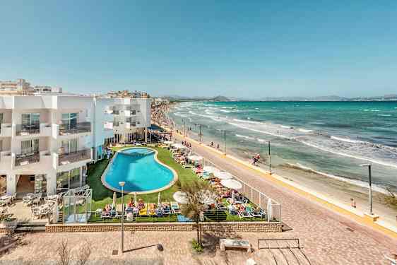 Hotellirakennus ja allasalue rantakadun ja hiekkarannan vieressä. (Tekoälyn luoma teksti)