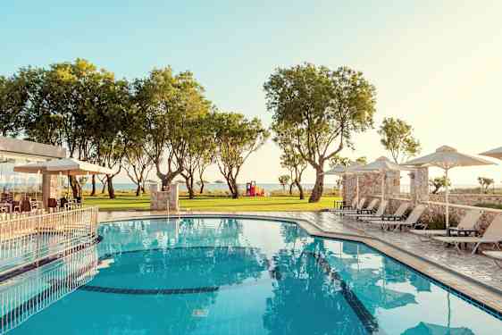 Uima-allas, jossa on aurinkotuoleja ja päivänvarjoja, ympärillä vehreää aluetta ja puita. (Tekoälyn luoma teksti)