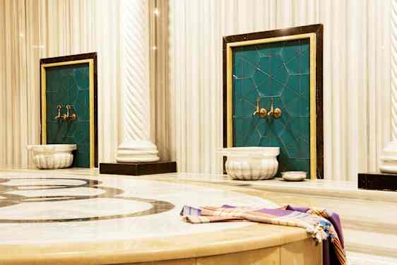 Kuva perinteisestä hamamista, jossa on marmoria ja vesihanoja. (Tekoälyn luoma teksti)