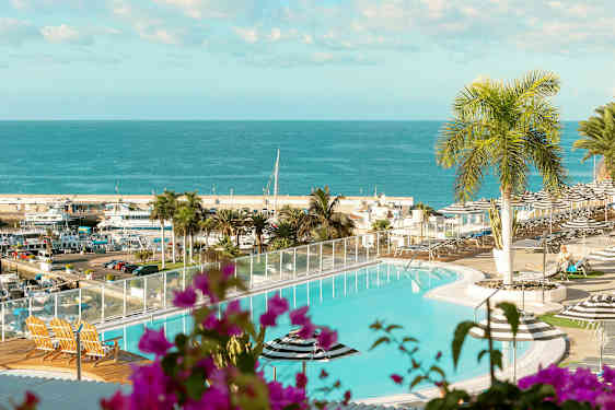 Uima-allas, josta on näkymä merelle ja satamaan. Etualalla on kasveja ja ulkokalusteita. (Tekoälyn luoma teksti)