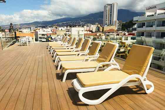 Kattoterassi, jossa on aurinkotuoleja ja näkymä kaupunkiin sekä ympäröiviin vuoriin. (Tekoälyn luoma teksti)