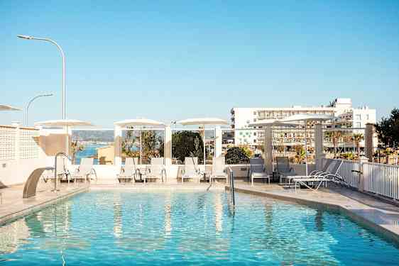 Ulkouima-allas aurinkotuoleilla ja -varjoilla, taustalla näkyy rakennuksia ja meri. (Tekoälyn luoma teksti)