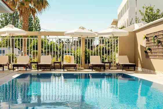 Ulkoallas, jonka reunalla aurinkotuoleja ja aurinkovarjoja. (Tekoälyn luoma teksti)