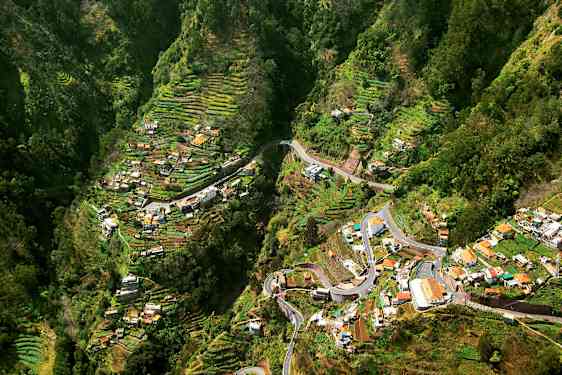 Näköala laaksoon, jossa on pengerettyjä viljelyalueita ja taloja. (Tekoälyn luoma teksti)