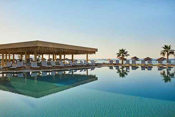 Ulkouima-allas, jossa on aurinkotuoleja ja aurinkovarjoja meren rannalla. (Tekoälyn luoma teksti)