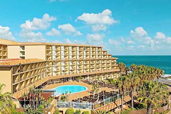 Hotellirakennus parvekkeineen, uima-allasalue ja meri taustalla. (Tekoälyn luoma teksti)