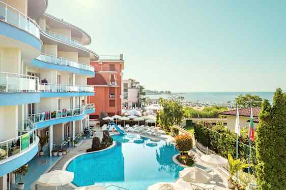 Kuva hotellista meren äärellä, jossa on uima-allas ja sitä ympäröivää vehreyttä. (Tekoälyn luoma teksti)