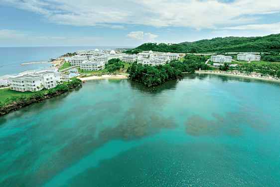 Kuva rannikon kirkkaasta vedestä ja valkoisista rakennuksista, joita ympäröi vihreä luonto. (Tekoälyn luoma teksti)