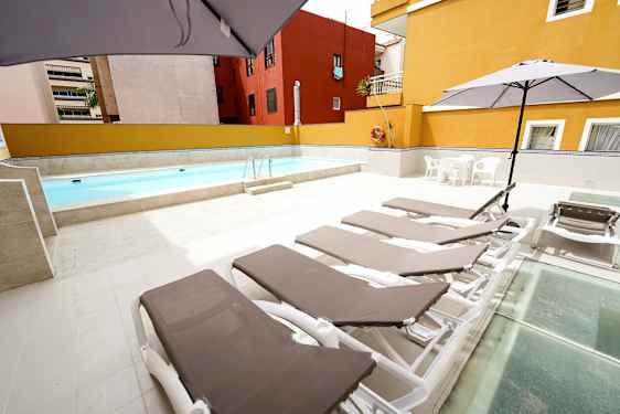 Ulkouima-allas, jonka ympärillä on aurinkotuoleja ja aurinkovarjoja kivetyksellä. (Tekoälyn luoma teksti)