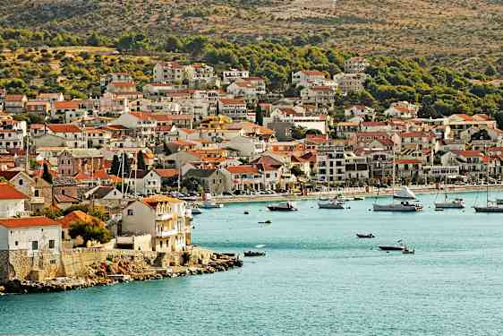 Rannikkokaupunki, jossa taloja lähellä vedenrantaa ja veneitä lahdella. (Tekoälyn luoma teksti)