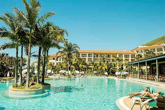 Lämmitetty ulkouima-allas, jota ympäröivät palmupuut, monikerroksisen hotellin lähellä. (Tekoälyn luoma teksti)