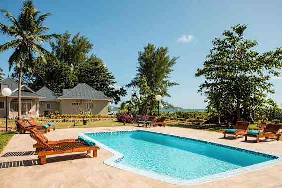 Suuri kuva uima-altaasta, jota ympäröivät aurinkotuolit kompleksissa. (Tekoälyn luoma teksti)