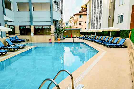 Ulkouima-allas, jota ympäröivät aurinkotuolit ja rakennukset. (Tekoälyn luoma teksti)