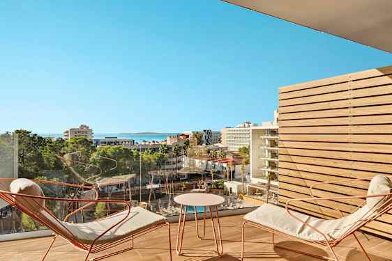 Näkymä kaupunkiympäristöön, jossa hotelleja ja viheralueita, parvekkeelta oleskelutiloineen. (Tekoälyn luoma teksti)