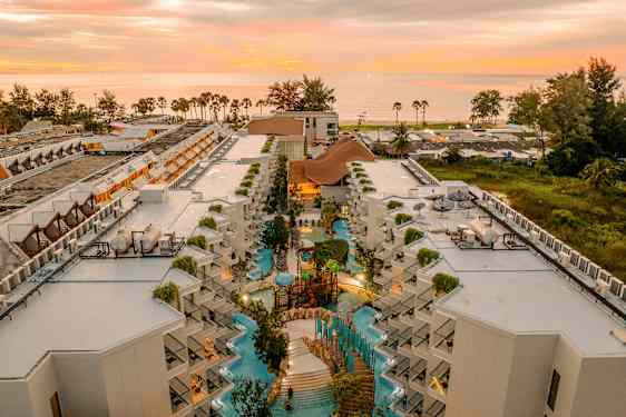 Ilmakuva hotellikompleksista, jossa on allasalue ja auringonlasku taustalla. (Tekoälyn luoma teksti)