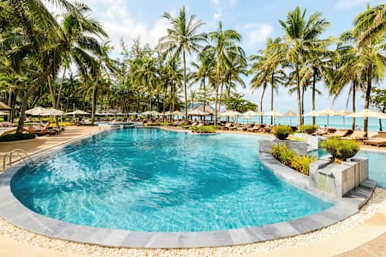 Ulkouima-allas, jota ympäröivät aurinkotuolit ja aurinkovarjot trooppisessa lomakohteessa. (Tekoälyn luoma teksti)