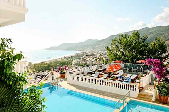 Näkymä altaalle, aurinkotuoleille, merelle ja rannikkokaupunkiin taustalla. (Tekoälyn luoma teksti)