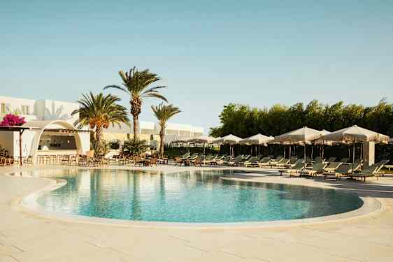 Ulkouima-allas aurinkotuoleilla ja -varjoilla, ympäröity palmuilla ja rakennuksella, jossa on baari. (Tekoälyn luoma teksti)