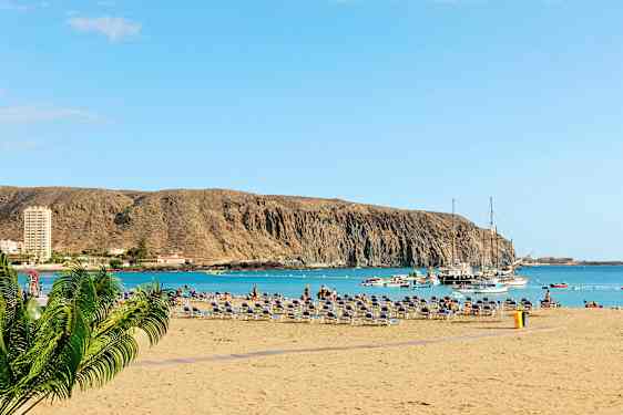 Ranta aurinkotuoleilla, meri ja veneitä kallion edustalla. (Tekoälyn luoma teksti)