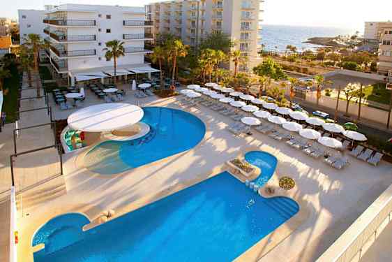 Hotellialue lähellä merta, jossa on uima-allas, aurinkotuoleja ja aurinkovarjoja. (Tekoälyn luoma teksti)