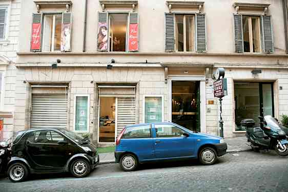 Rakennuksen julkisivu, edessä pysäköityjä autoja. (Tekoälyn luoma teksti)