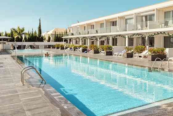 Hotellin uima-allas aurinkotuoleilla ja varjoilla sivuilla. (Tekoälyn luoma teksti)