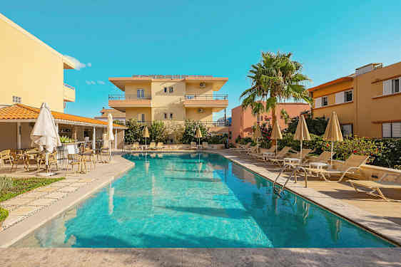 Ulkoallas, jota ympäröivät aurinkotuolit ja aurinkovarjot, taustalla rakennuksia. (Tekoälyn luoma teksti)