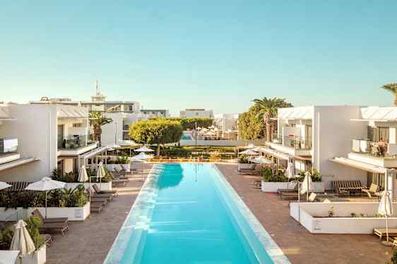 Ulkouima-allas, jota ympäröivät modernit valkoiset rakennukset, joissa on parvekkeita ja aurinkotuoleja varjojen alla. (Tekoälyn luoma teksti)