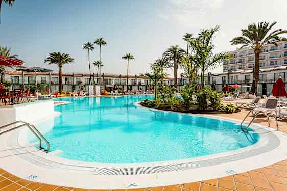 Ulkouima-allas, jota ympäröivät aurinkotuolit ja palmut hotellin vieressä. (Tekoälyn luoma teksti)