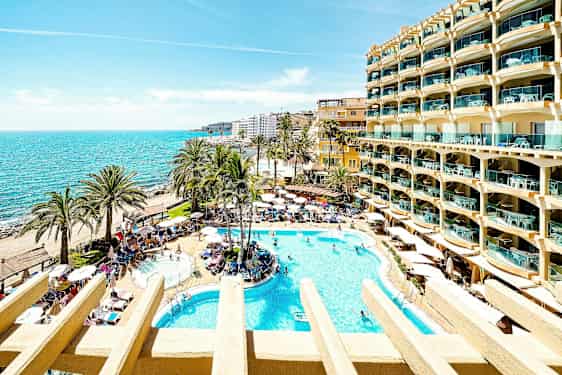 Aurinkoinen hotellipiha uima-altaineen, palmuineen ja merinäköalalla. (Tekoälyn luoma teksti)