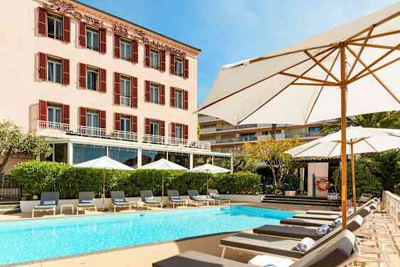 Hotellirakennus, jonka edessä on uima-allas ja aurinkotuoleja. (Tekoälyn luoma teksti)