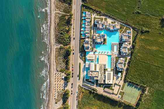 Ilmakuva lomakohteesta, jossa on uima-altaita ja rakennuksia meren läheisyydessä. (Tekoälyn luoma teksti)