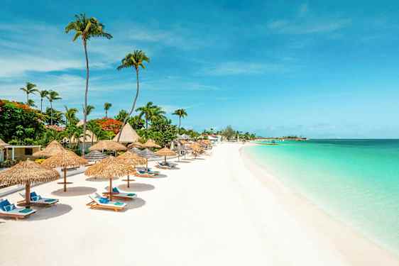 Ranta, jossa on aurinkovarjoja ja rantatuoleja turkoosin veden äärellä. (Tekoälyn luoma teksti)