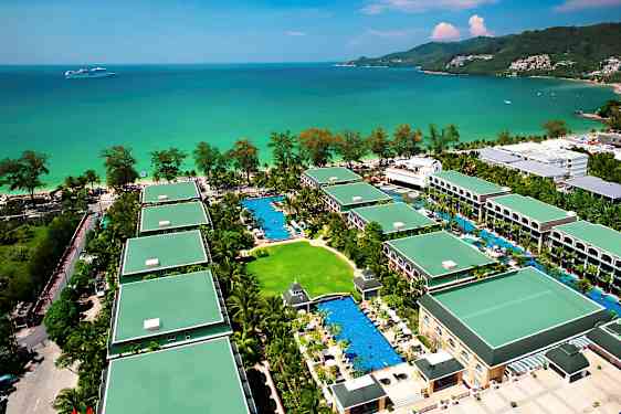 Ilmakuva lomahotellista, jossa on useita rakennuksia vehreyden ja uima-altaiden ympäröimänä lähellä merta. (Tekoälyn luoma teksti)