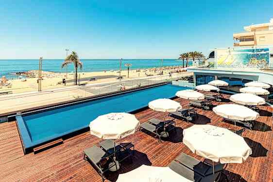 Ulkouima-allas aurinkotuoleineen ja aurinkovarjoineen sekä hiekkaranta merinäköalalla. (Tekoälyn luoma teksti)