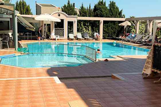 Ulkoallas, jossa on aurinkotuoleja, aurinkovarjoja ja ihmisiä nauttimassa ympäristöstä. (Tekoälyn luoma teksti)