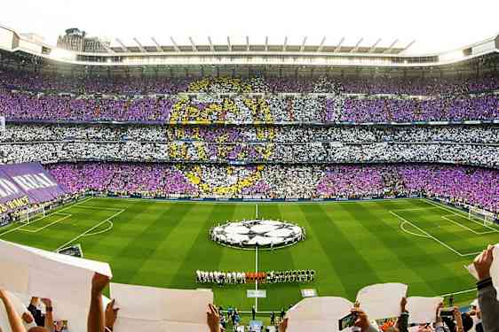 Täysi jalkapallostadion, jossa värillinen yleisökuvio ja joukkueet kentällä. (Tekoälyn luoma teksti)