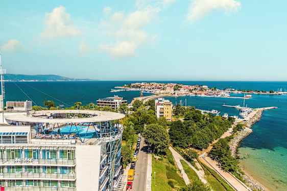 Kuva rannikkokaupungista, taustalla meri. Etualalla suuri rakennus, jonka katolla on uima-allas. (Tekoälyn luoma teksti)