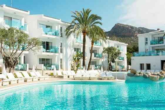 Kuva hotellista, jossa on valkoisia rakennuksia, uima-allas ja aurinkotuoleja, ympärillä palmuja. (Tekoälyn luoma teksti)