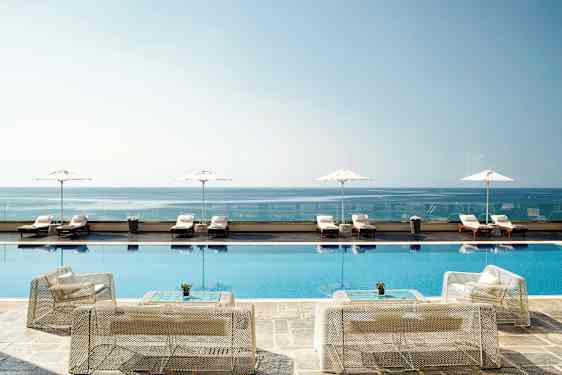 Kuva infinity-altaasta rannikolla, taustalla aurinkotuoleja ja aurinkovarjoja. (Tekoälyn luoma teksti)