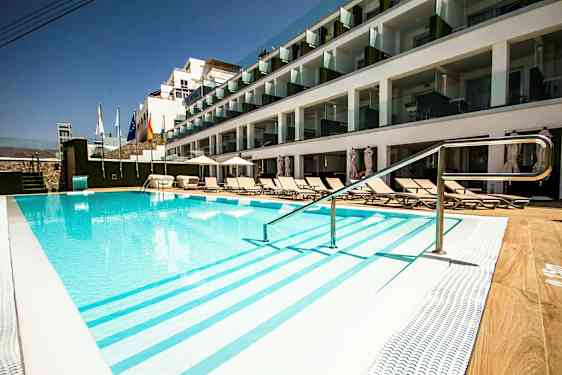 Ulkouima-allas hotellilla, jossa on aurinkotuoleja ja lasiparvekkeita. (Tekoälyn luoma teksti)