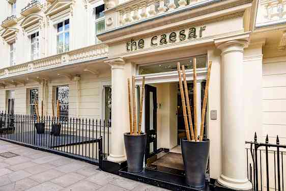 Hotelli The Caesarin sisäänkäynti, jota ympäröi musta rautaportti. (Tekoälyn luoma teksti)