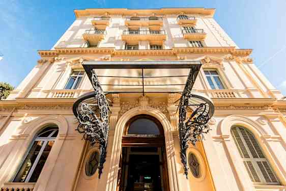 Rakennus, jossa on useita kerroksia ja tyylikästä koristeellisuutta, nähtynä kadun tasolta. (Tekoälyn luoma teksti)