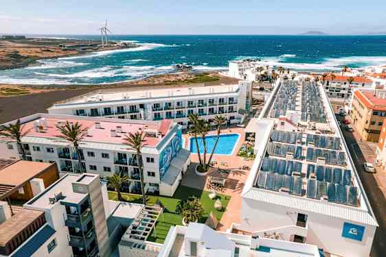 Hotellialue, jossa on uima-allas, rakennusten ympäröimänä, näkymä merelle ja aaltoihin. (Tekoälyn luoma teksti)