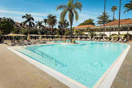 Ulkouima-allas, ympärillä aurinkotuoleja ja aurinkovarjoja, taustalla palmuja. (Tekoälyn luoma teksti)